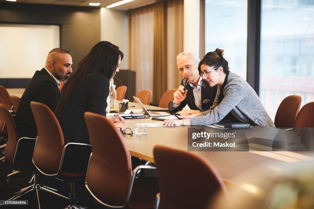 Male and female lawyers discussing over document at conference table in meeting