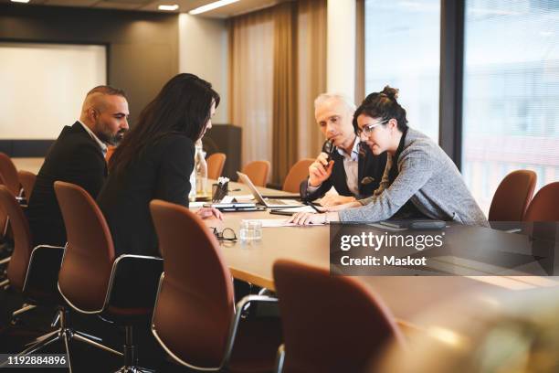 male and female lawyers discussing over document at conference table in meeting - law office imagens e fotografias de stock