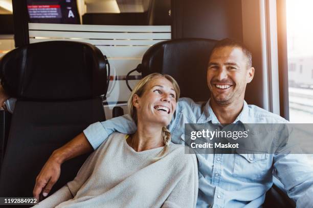 happy couple enjoying journey in train - couple in a train stock pictures, royalty-free photos & images