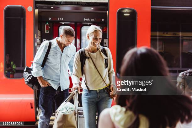 happy family with luggage standing at railroad platform against train - familie in der bahn stock-fotos und bilder