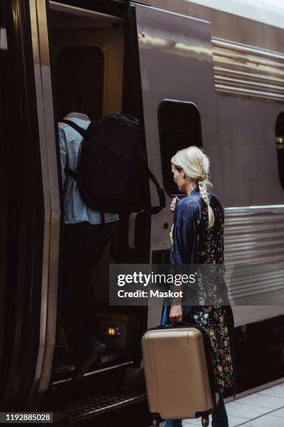 couple with luggage boarding train at station - man woman train station stockfoto's en -beelden