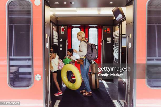 mother and children with luggage walking in train at station - train photos et images de collection