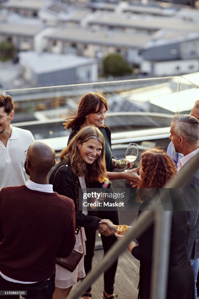 Happy professionals greeting at party on terrace after work
