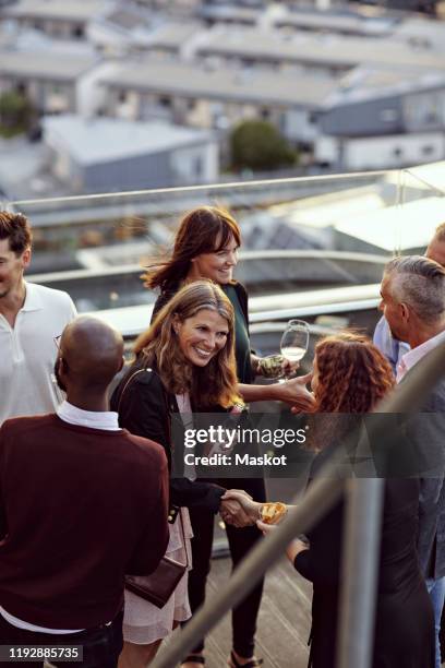 happy professionals greeting at party on terrace after work - business party stockfoto's en -beelden