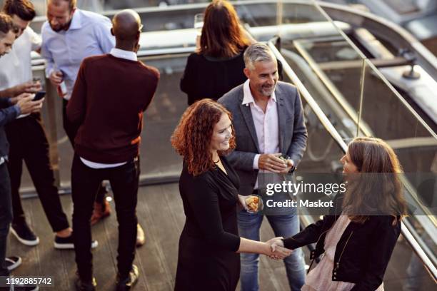 high angle view of businesswoman doing handshake and greeting while partying with coworkers after work on terrace - leaving work stock pictures, royalty-free photos & images