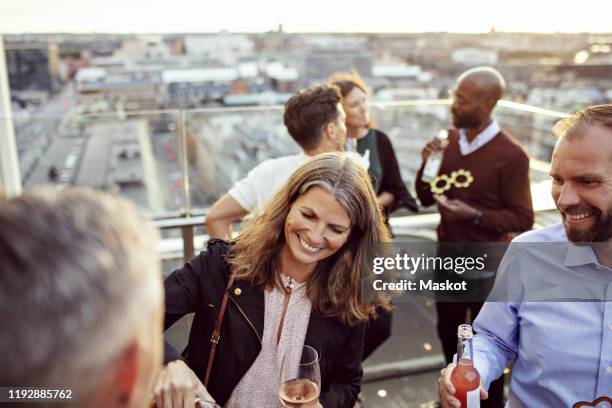 happy male and female coworkers enjoying drinks in party after work - blaue stunde stock-fotos und bilder