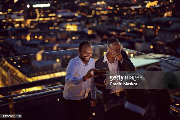 happy professionals taking selfie on smart phone while standing on terrace in city - office party stock pictures, royalty-free photos & images