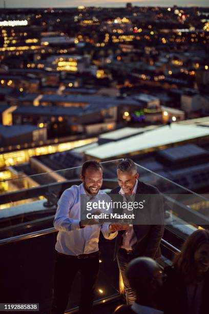high angle view of cheerful businessmen taking selfie on smart phone while standing on terrace after work in illuminated - kick off call stock pictures, royalty-free photos & images