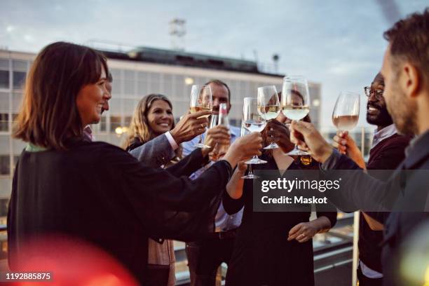 business coworkers toasting wineglasses while celebrating in office party on terrace - business party photos et images de collection