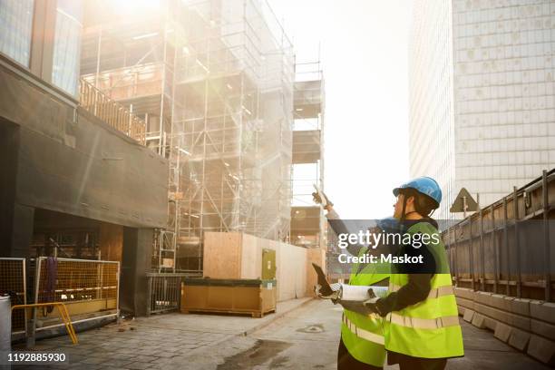 female engineers in reflective clothing discussing at construction site - womens draft ストックフォトと画像