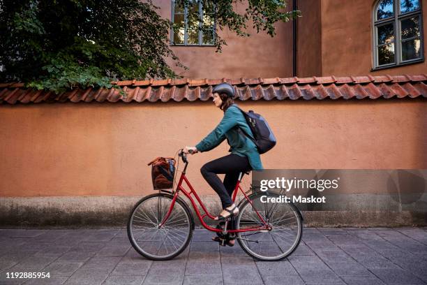 side view of female engineer riding bicycle on street in city - commuter cycling stock pictures, royalty-free photos & images