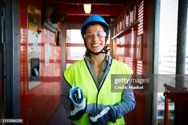 portrait of smiling female engineer in reflective clothing at construction site - womens draft ストックフォトと画像