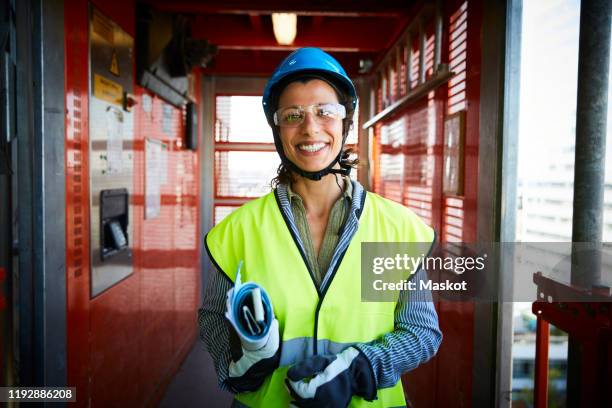 portrait of smiling female engineer in reflective clothing at construction site - protective eyewear stock pictures, royalty-free photos & images