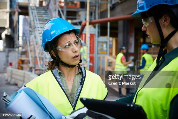 female engineer discussing with coworker at construction site - womens draft ストックフォトと画像