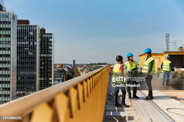 female and male engineers discussing at construction site against sky - bakgrundsfokus bildbanksfoton och bilder