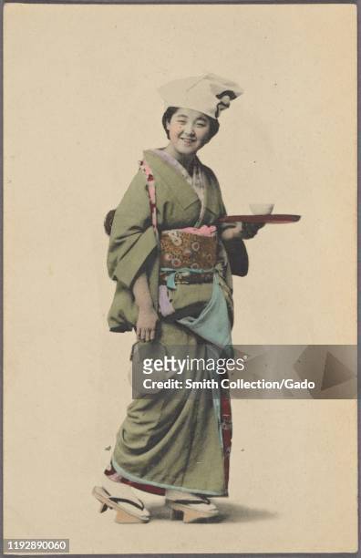 Illustrated postcard of a young Japanese woman wearing a traditional kimono, carrying a teapot, a serving tray and cup, Japan, 1904. From the New...