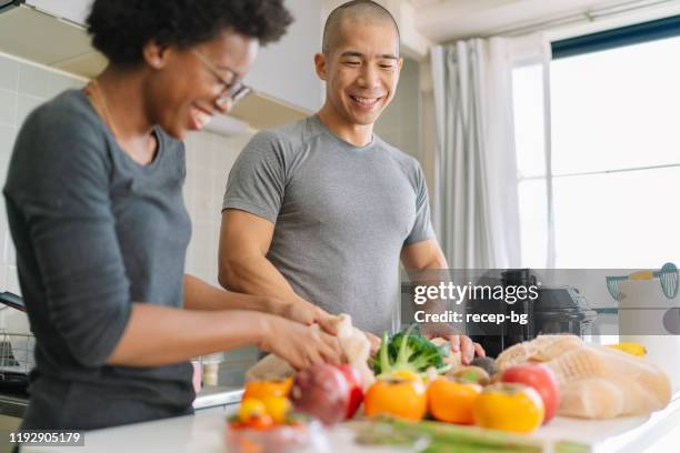 young couple preparing vegan food at home - young man groceries kitchen stock pictures, royalty-free photos & images