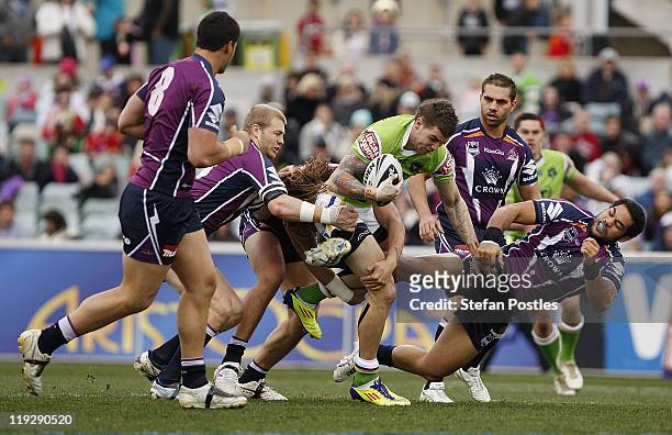 Josh Dugan of the Raiders is tackled during the round 19 NRL match between the Canberra Raiders and the Melbourne Storm at Canberra Stadium on July...