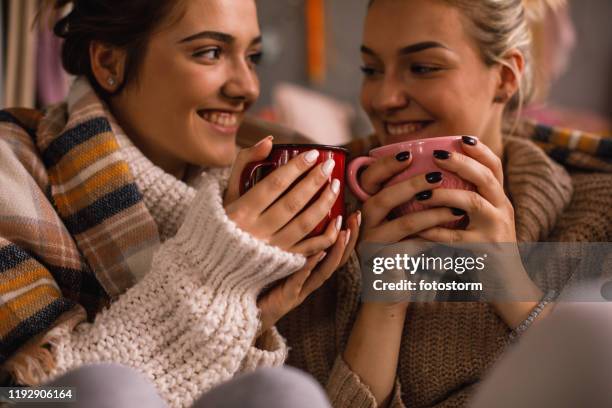 corte de amigas femeninas sonrientes compartiendo una bebida agradable y acogedora - chocolate liquido fotografías e imágenes de stock