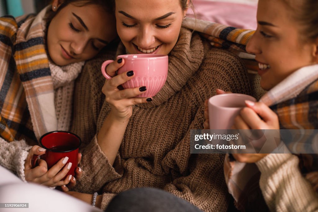 High angle view of three pretty female friends sharing hot beverages