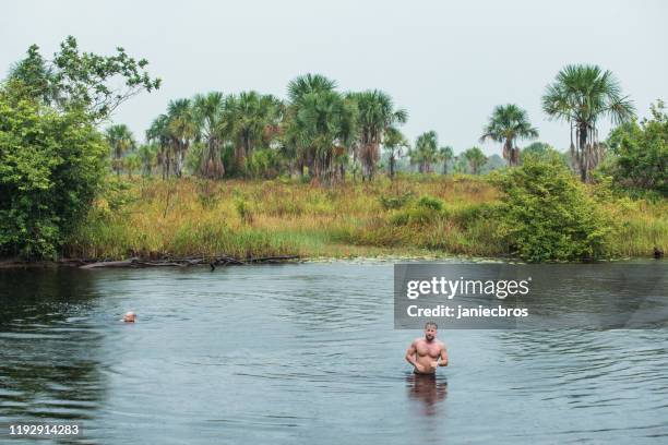man standing in the jungle river during heavy rain - guyana stock pictures, royalty-free photos & images