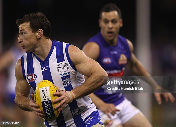 Brent Harvey of the Kangaroos collects the ball in front of Lindsay Gilbee of the Bulldogs during the round 17 AFL match between the North Melbourne...