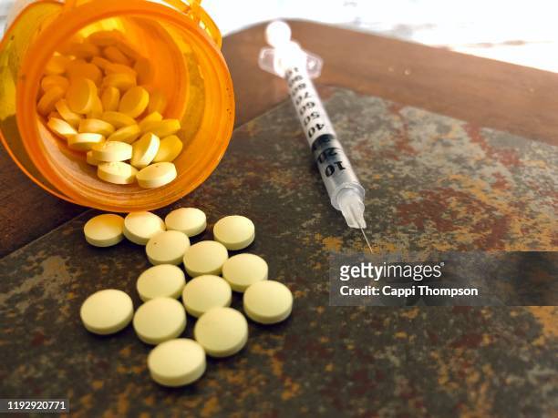 opioid pills with syringe - opioid stock-fotos und bilder