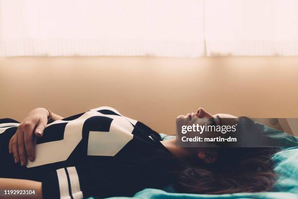 depressed teenage girl lying down in bed - miscarriage stock pictures, royalty-free photos & images