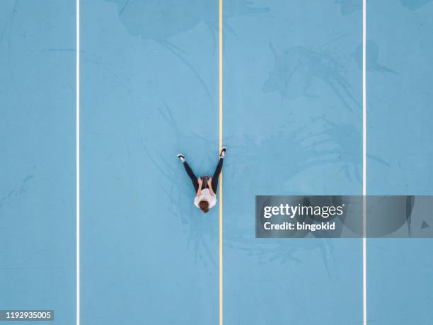 woman sitting on skateboard in blue school yard - sports centre exterior stock pictures, royalty-free photos & images