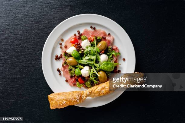 appetizer of; carpaccio, tomatoes,ruccola,pesto, mozzarella and balsamic vinegar caviar. - above food stock pictures, royalty-free photos & images