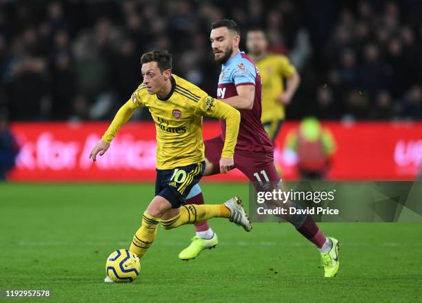 Mesut Ozil of Arsenal under pressure from Robert Snodgrass of West Ham during the Premier League match between West Ham United and Arsenal FC at...