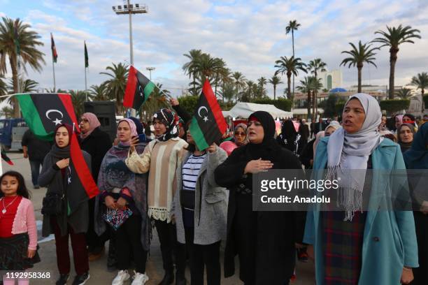 Women hold flags during a demonstration against eastern military commander Khalifa Haftar, who is based in the east of the country, and in support of...
