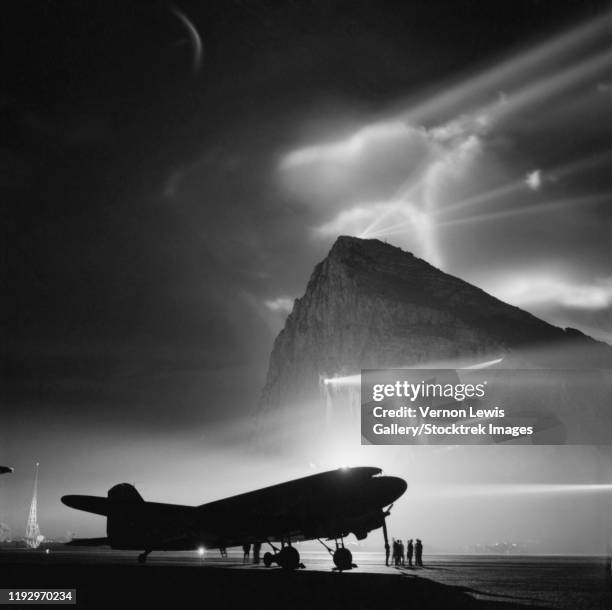 a dakota passenger plane silhouetted by searchlights from the rock of gibraltar. - pedra de gibraltar - fotografias e filmes do acervo