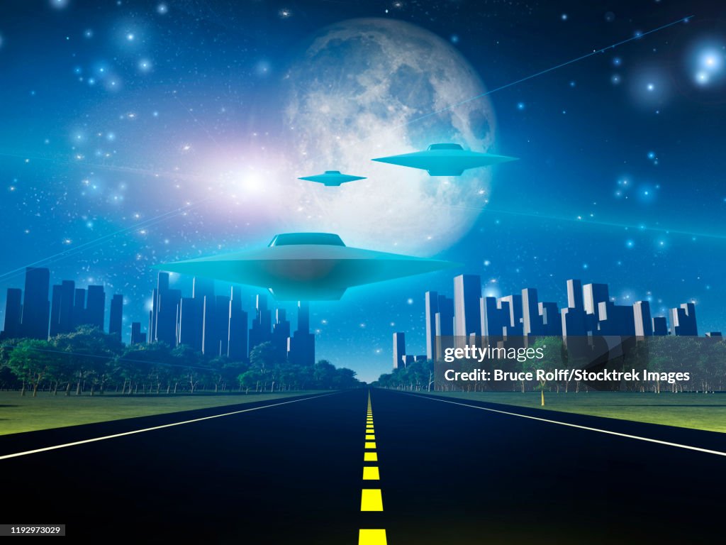 Highway to city with large moon and alien ships.
