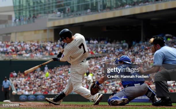 Joe Mauer of the Minnesota Twins hits an RBI single as Matt Treanor of the Kansas City Royals catches in the first inning on July 17, 2011 at Target...