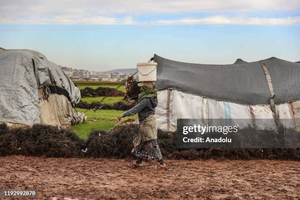 Syrian woman carries a bucket on her head at a camp hosting Syrian families, who have been forced to displace due to the attacks carried out by Assad...