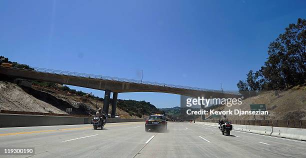 California Highway Patrol officers lead motorist before they pass under the Mulholland Bridge on the Interstate 405 after it re-opened ahead of...