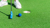 Close up of a club prepares to hit a ball during a mini golf game.
