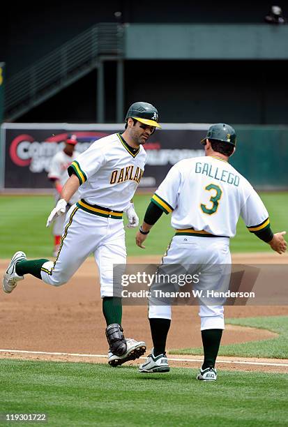 Conor Jackson of the Oakland Athletics hits a grand-slam and rounds third base to slap the hand of coach Mike Gallego against the Los Angeles Angels...