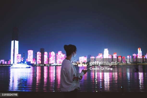 man using a mobile phone in the city at night - wuhan stock-fotos und bilder