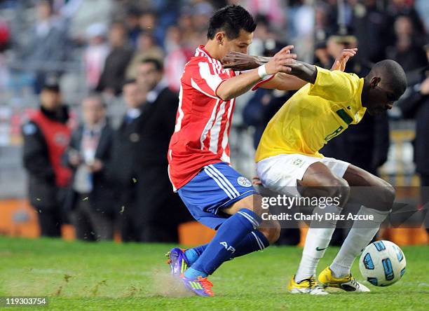 Ramires Santos of Brazil struggles for the ball with Hernan Perez of Paraguay during a match as part of the Copa America 2011 at the Ciudad de La...