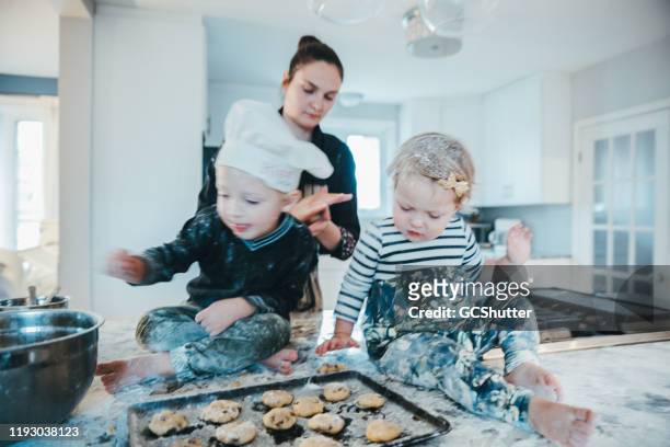 kinder spielen mit keksteig an der küchentheke - young women group back stock-fotos und bilder
