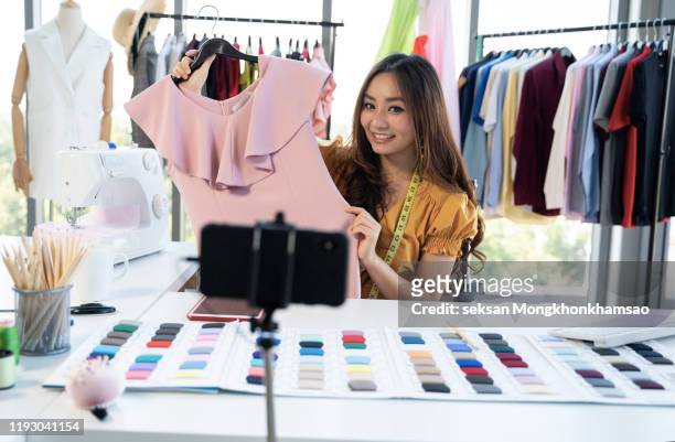 beauty female fashion vlogger presenting dress to cellphone and showing clothes selling online live streaming - live streaming bildbanksfoton och bilder