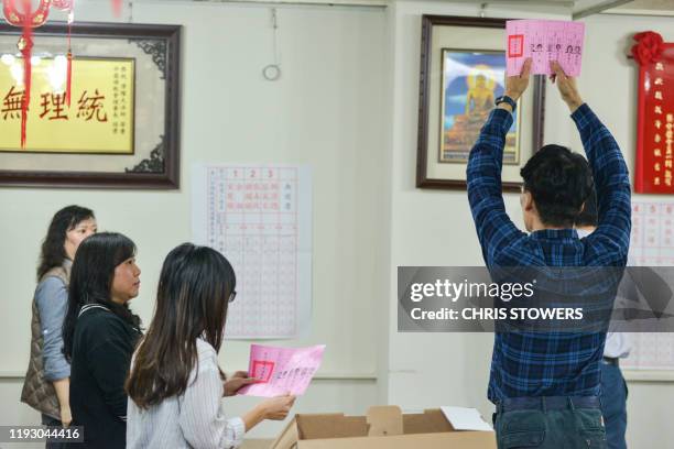 An electoral official holds up a ballot slip and announces the name of the chosen candidate on it, at a polling station in Shandao Temple in central...