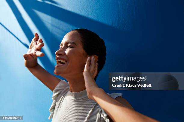 smiling woman against blue wall - low depth of field photos et images de collection