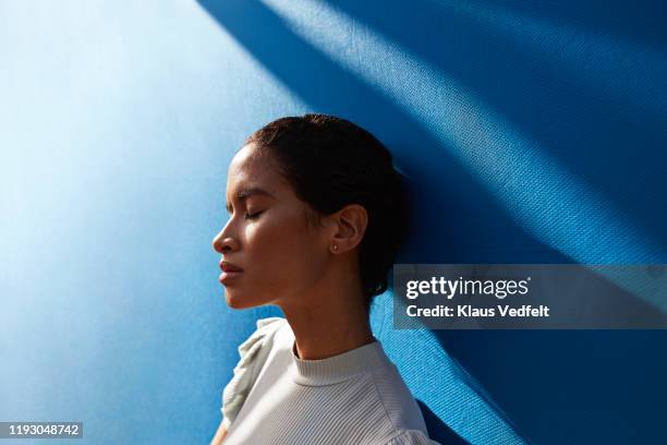 beautiful woman standing against blue wall - fashion for peace stockfoto's en -beelden