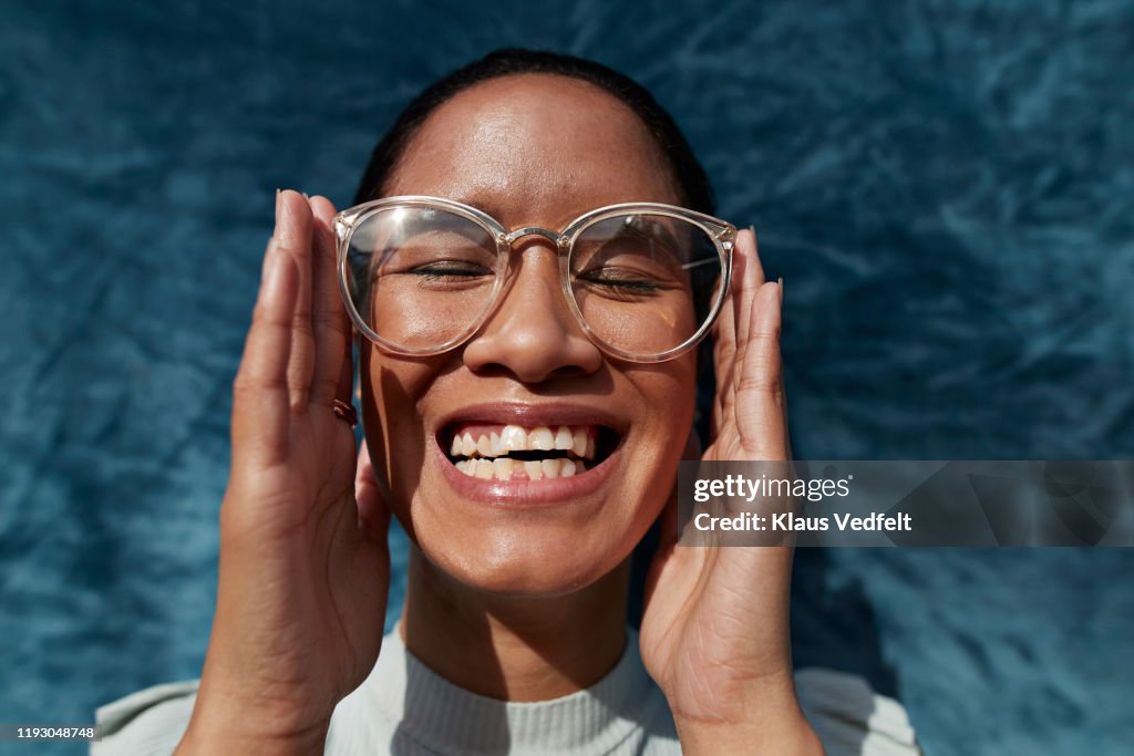 Smiling woman wearing eyeglasses against blue wall
