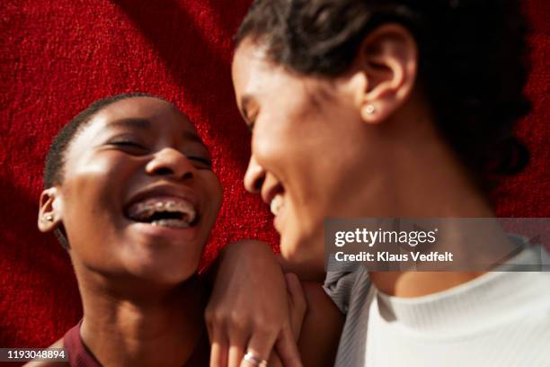 close-up of friends standing against red wall - black people laughing stock-fotos und bilder