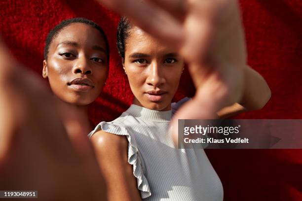 portrait of women gesturing against red wall - mode stock-fotos und bilder