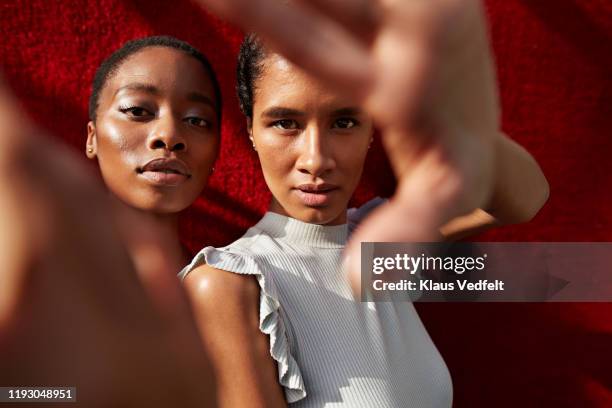 portrait of women gesturing against red wall - depth of field togetherness looking at the camera stock pictures, royalty-free photos & images